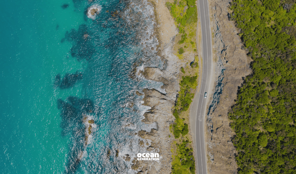 Car driving on a coastal road beside the Ocean. In this article, Ocean Generation shares why having roads made with recycled plastic has a negative impact on planet and human health.