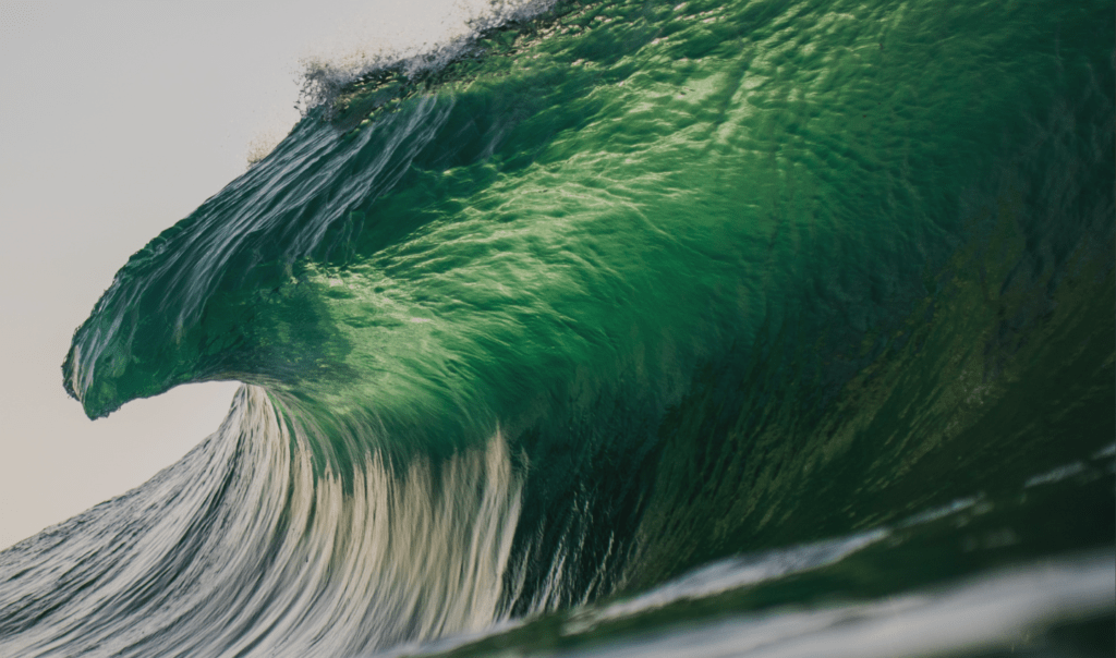 Breathtaking image of an Ocean wave breaking. The wave has a green hue. In this article, Ocean Generation explains why our Ocean is turning green because of climate change.